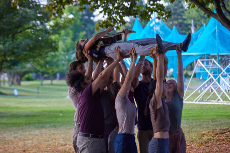 Mandolin player being carried above the heads of acrobats