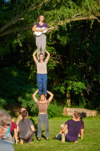 Playing mandolin on a three acrobat high pyramid